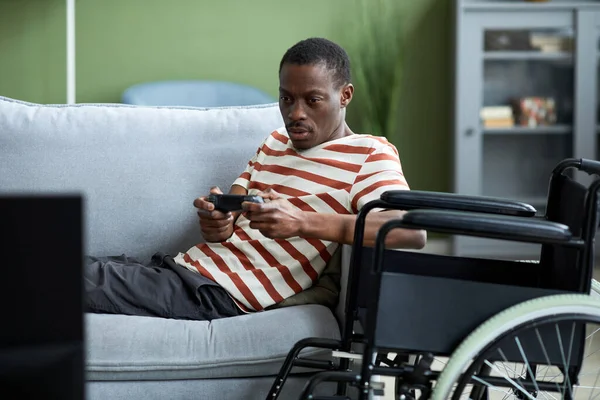 Portret Afroamerykanina Niepełnosprawnego Grającego Gry Wideo Domu Leżącego Kanapie Wózku — Zdjęcie stockowe
