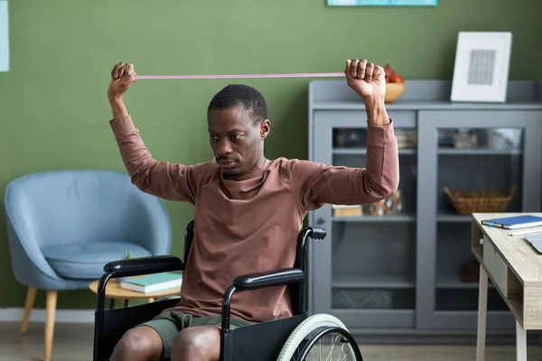 Minimalny Portret Dorosłego Czarnego Mężczyzny Niepełnosprawnego Ćwiczącego Domu Wykorzystaniem Elastycznych — Zdjęcie stockowe