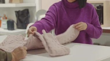 Esmer Ortadoğulu mağaza asistanı, tasarımcı galerisinde müşteriyle konuşurken dikkatlice katlıyor.