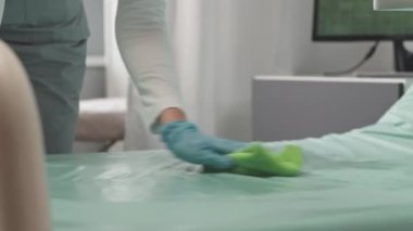 Yeni hastaya hazırlanırken hastane yatağını temizleyip sterilize eden tanınmayan hemşire iğnesi.