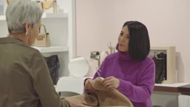 Genç çekici esmer Orta Doğulu kadın lüks tasarımcı galerisinde çalışırken müşteriyle konuşuyor.