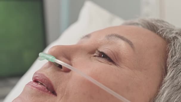 病院のベッドに横たわる鼻腔カヌーを持つ成熟したアジアの女性のクローズアップ 手術後のリハビリ — ストック動画