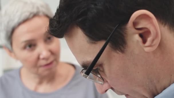 短い髪の成熟したアジアの女性と病院の部屋で会話している彼女の医師の最中閉鎖 — ストック動画