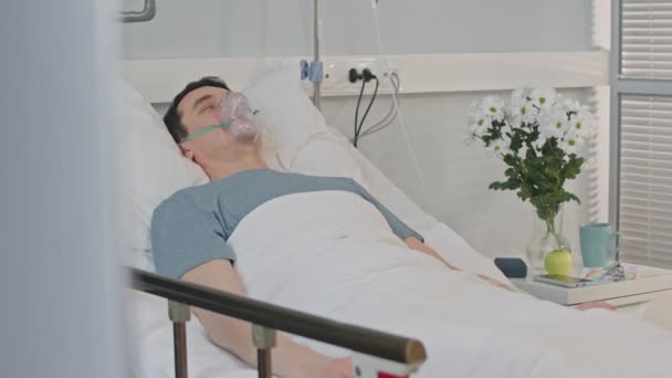 Fiatal Férfi Beteg Oxigénmaszkkal Arcán Eszméletlenül Fekszik Kórházi Ágyon — Stock videók