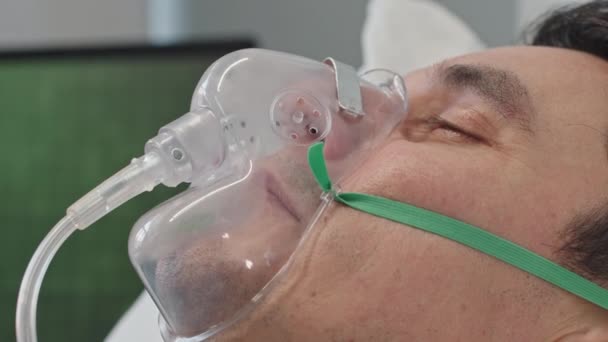 Closeup Homem Respirando Através Máscara Oxigênio Enquanto Deitado Cama Hospital — Vídeo de Stock