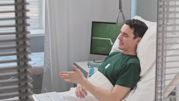 ベッドで休んでいる間 ラップトップで友人とチャットする病院のビデオで怪我から回復するコーカサス陸軍士官 — ストック動画