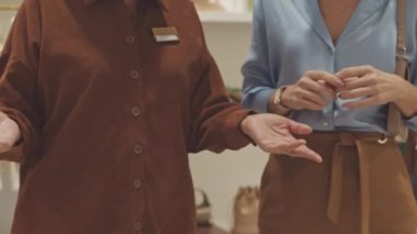 Mağaza asistanının müşteriye danışmanlık yaptığı ve tasarımcı butiğinde yeni giysiler ve aksesuar koleksiyonu sergilediği sahneler.