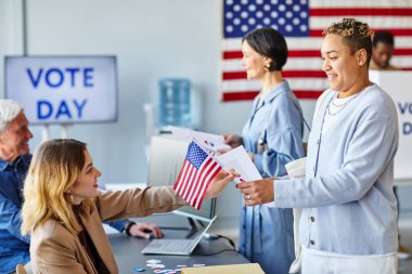 Amerikan bayrağıyla oy kullanan gülümseyen siyahi kadının yan görünümü