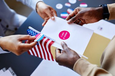 Seçim günü oy pusulası ve çıkartma tutan ellerin yakınlaştırılması, boşluğu kopyala