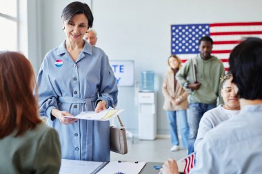 Oy kullanma merkezinde oy kullanan gülümseyen yetişkin bir kadının ön görünümü, boşluğu kopyala