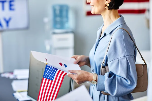 stock image Side view cropped shot of smiling woman holding voting ballot and American flag on election day