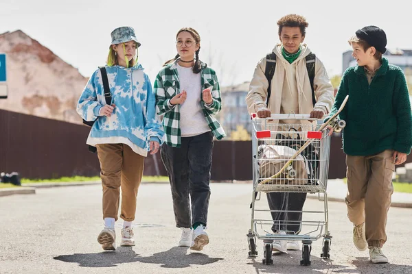 十代の若者のグループが通りを歩き 彼らのものとショッピングカートを運ぶ — ストック写真
