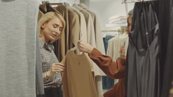 两名现代女性在设计精品店一起购物 讨论挂在衣架上的服装 — 图库视频影像