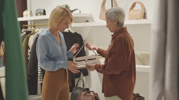 Елегантна Блондинка Вибирає Сумку Сучасному Дизайнерському Бутіку Помічник Жіночого Магазину — стокове відео