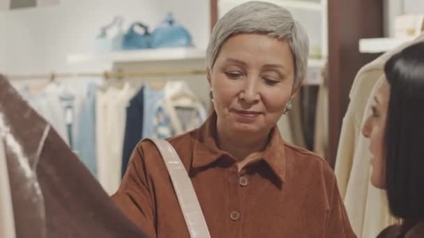 Consultor Loja Ajudando Mulher Asiática Madura Para Escolher Roupa Boutique — Vídeo de Stock