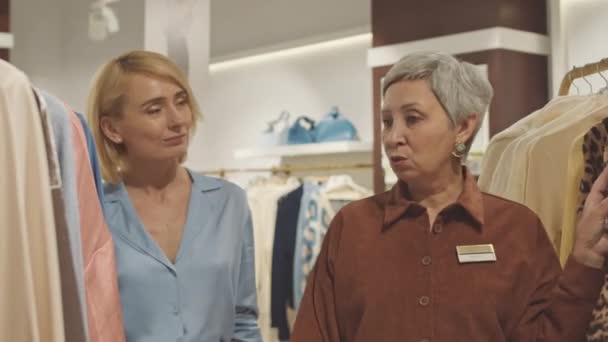 Помічник Жіночого Магазину Допомагає Елегантній Блондинці Купувати Одяг Дизайнерському Бутіку — стокове відео
