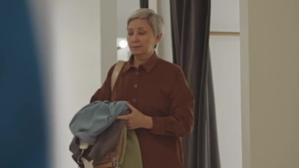 Ώριμη Ασιάτισσα Γυναίκα Που Κουβαλάει Μια Στοίβα Ρούχα Στα Χέρια — Αρχείο Βίντεο