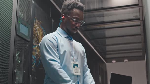 Ujęcie Blokady Skoncentrowanego Młodego Afroamerykańskiego Technika Komputerowego Pracującego Laptopie Szafie — Wideo stockowe