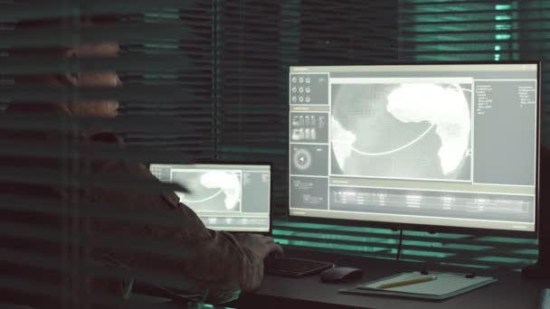 アジアの軍事監視官が都市追跡作戦に取り組んでおり 暗い中央オフィスのハブでコンピュータ上の衛星カメラを監視している — ストック動画