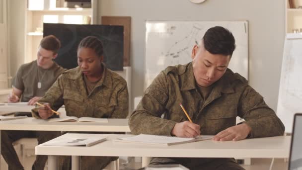 軍事アカデミーの教室で机に座っている多様なキャデットのスローモーションを待つ — ストック動画