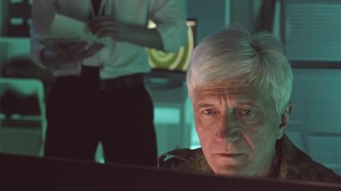 Kamuflaj üniformalı beyaz saçlı gözetleme komutanı yavaş yavaş bilgisayar ekranındaki hedefi izliyor ve merkez ofis merkezinde çalışan meslektaşlarına telefon açıyor.