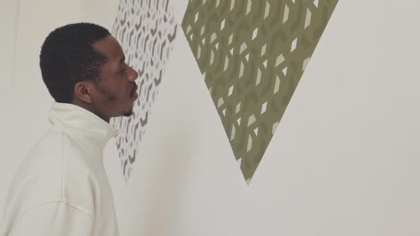 Afro Américain Debout Près Motifs Minimalistes Images Sur Mur Blanc — Video