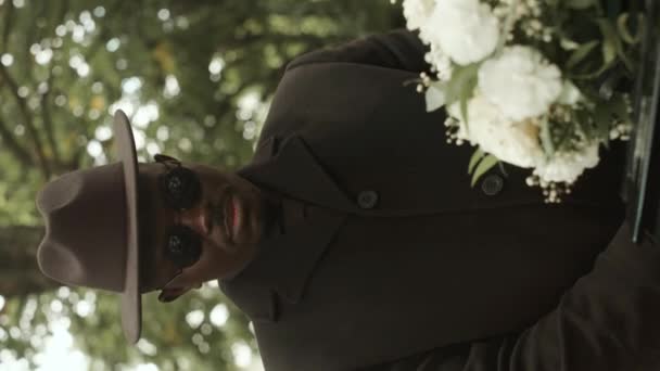 Pionowe Ujęcie Opłakującego Afroamerykanina Czarnym Płaszczu Okularach Przeciwsłonecznych Stojącego Cmentarzu — Wideo stockowe