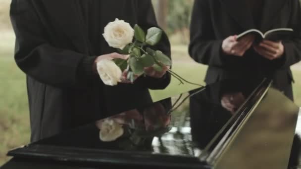 Tiro Cortado Viúva Irreconhecível Casaco Preto Longo Colocando Rosas Brancas — Vídeo de Stock