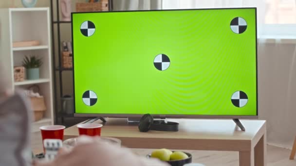 在现代客厅的桌子上复制一个绿色的空间电视显示屏 上面有无法辨认的人在切换频道 — 图库视频影像