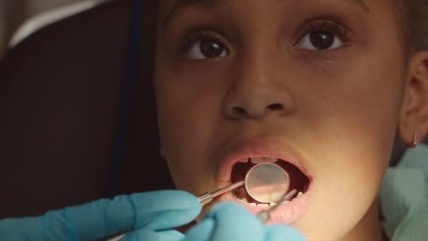 6歳のアフリカ系アメリカ人の少女が歯の椅子で口を開け 歯科クリニックで小児歯科医に診察を受けた — ストック動画
