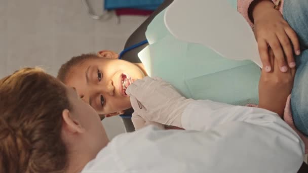 6歳のアフリカ系アメリカ人の少女が診療所で女性歯科医に歯を検査した垂直撮影 — ストック動画