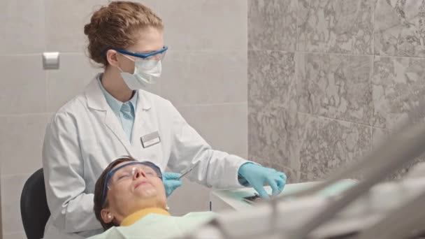 無菌ステンレス鋼のハンドピースを使用して女性歯科医に歯科チェアに横たわる白人女性 — ストック動画