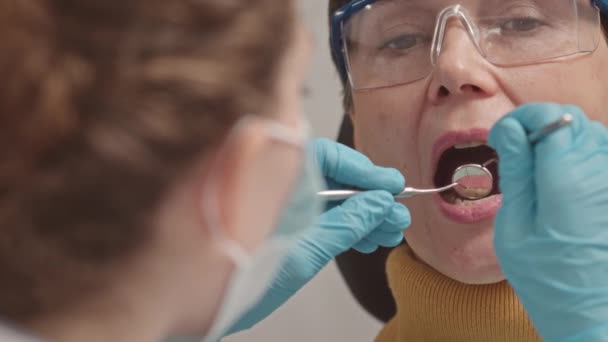 歯科用ハンドピースを使用した女性歯科医の中型閉鎖 歯科椅子の中の成人女性の歯と口腔の検査 — ストック動画