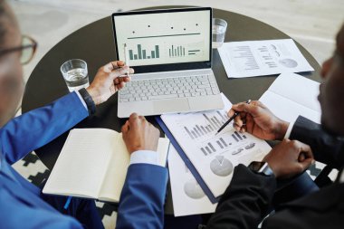 Finans yöneten ve veri tablolarına işaret eden iki başarılı iş adamının üst görünümü, boşluğu kopyala