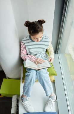 Pencerede otururken kitap okuyan güzel bir kızın dikey üst görünüm portresi