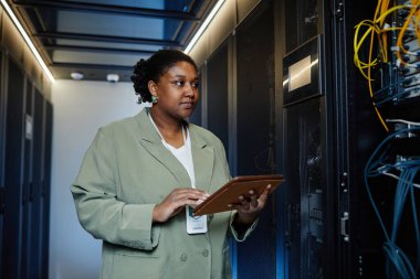 Sunucu odasında dizüstü bilgisayar kullanan ve şirket ağını yöneten kadın bilişim teknisyeninin belindeki portreyi kopyala