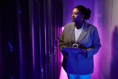 Sunucu odasındaki veri ağını inceleyen kadın sistem yöneticisinin portresi neon ışığı ile aydınlatılıyor, kopyalama alanı
