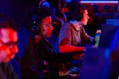 Neon ışığı altında çeşitli eSports takımlarıyla video oyunu oynayan genç siyahi adamın yan görünüm portresi