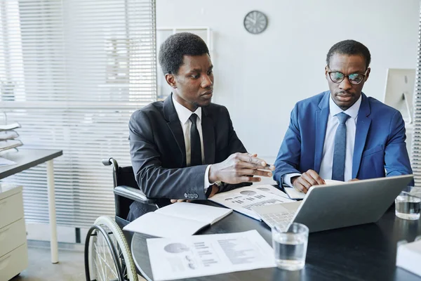 Portrait of African American man with disability in business meeting with partner discussing financial statistics, copy space
