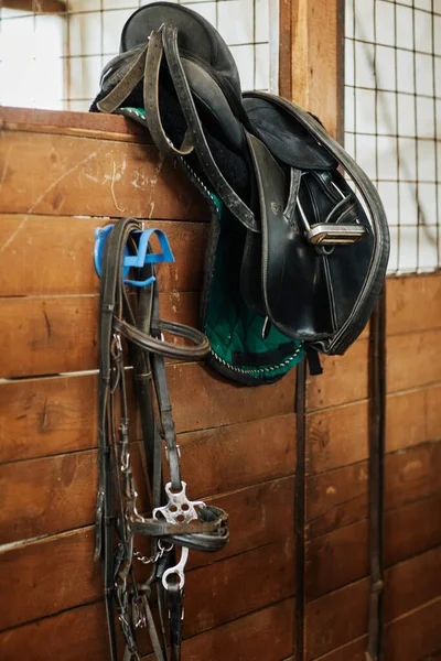 Close up of leather saddle and equestrian gear in wooden horse stables, country living