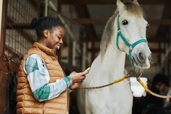 Boční Pohled Portrét Usmívající Afroameričanky Pomocí Smartphonu Koňských Stájích Bílým — Stock fotografie