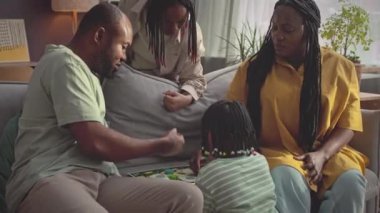 Dört kişilik modern Afro-Amerikan ailesi boş zamanlarında rahat bir oturma odasında oyun oynuyorlar.