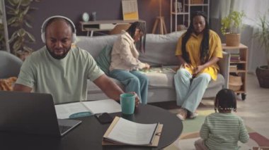 Dört kişilik modern Afro-Amerikan ailesi evde birlikte kalıyorlar. Babam dizüstü bilgisayarda çalışırken annem parlak oturma odasında iki küçük kızla oynuyor.