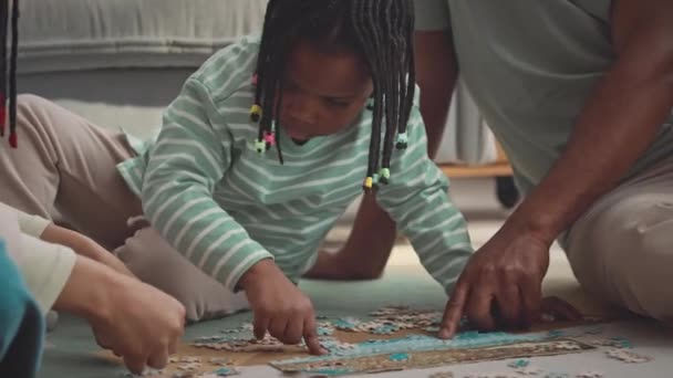 非洲裔美国人父亲带着小女儿在客厅地板上玩拼图游戏的偷拍镜头 — 图库视频影像