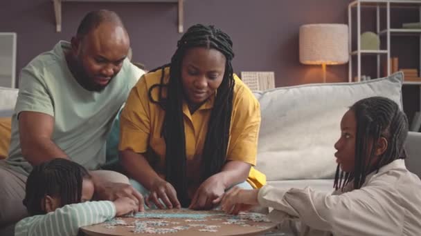 Glückliche Moderne Schwarze Vierköpfige Familie Löst Gemeinsam Puzzle Auf Couchtisch — Stockvideo