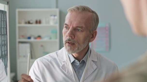 Orta Yaşlı Erkek Doktorun Omuz Üstünden Sonuçlarını Modern Klinikteki Hastalarla — Stok video