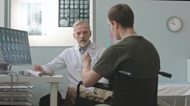 약속을 의사를 방문하는 휠체어에있는 컴퓨터 모니터에서 Mri 스캔을보고 대화를 나누는 — 비디오