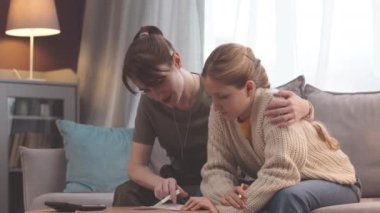Küçük kızına matematik ödevinde yardım ederken beyaz bir kadının hesap makinesi kullanırken orta boy fotoğrafı.