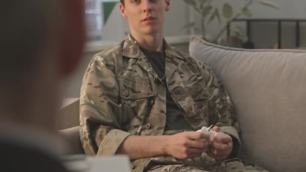 カモフラージュの制服の若い白人軍士官の肩のショットで 居心地の良い医師事務所で軍心理学者と彼の精神的問題を共有 — ストック動画