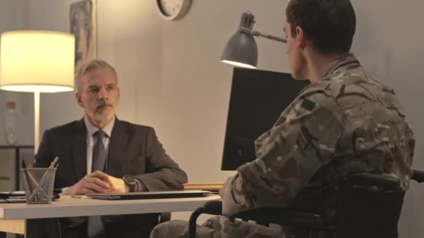 年轻的白人士兵坐在轮椅上 向成熟的男性精神病医生讲述他的精神问题 — 图库视频影像